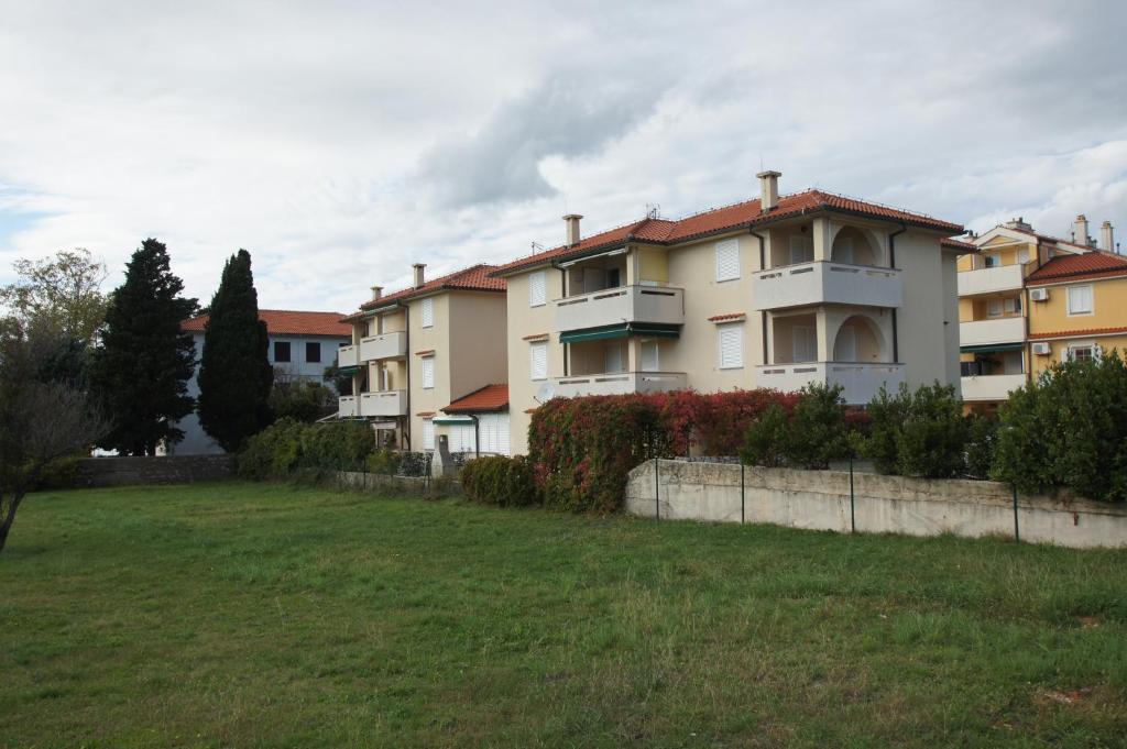 a group of houses in a field next to a yard at Apartments with a parking space Punat, Krk - 15231 in Punat