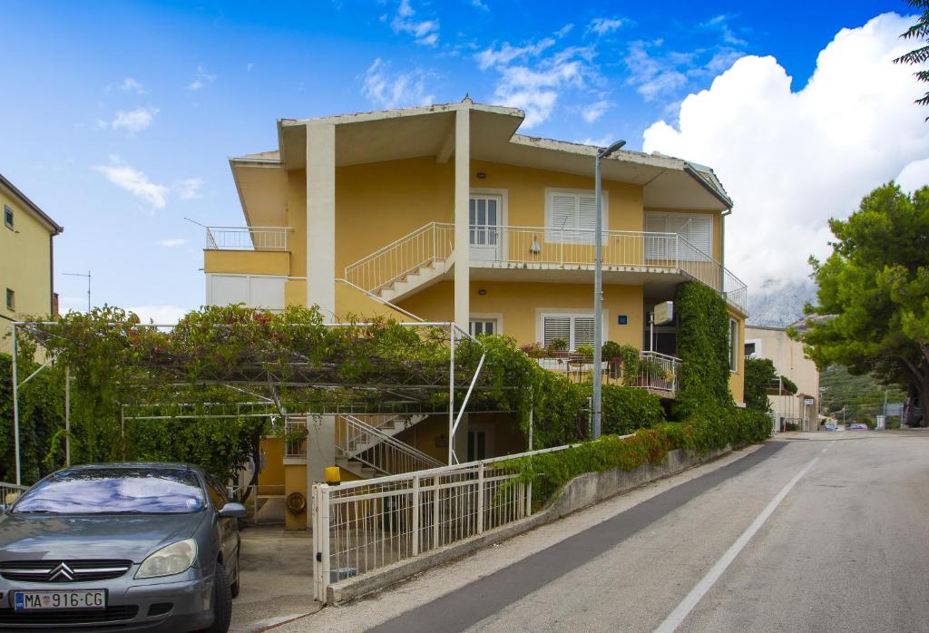 a yellow house with a car parked in front of it at Studio Podgora 12816c in Podgora