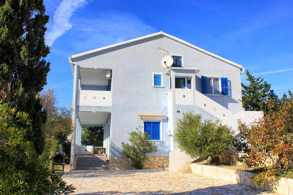 a white house with blue windows on a blue sky at Apartment Stara Novalja 9368b in Novalja