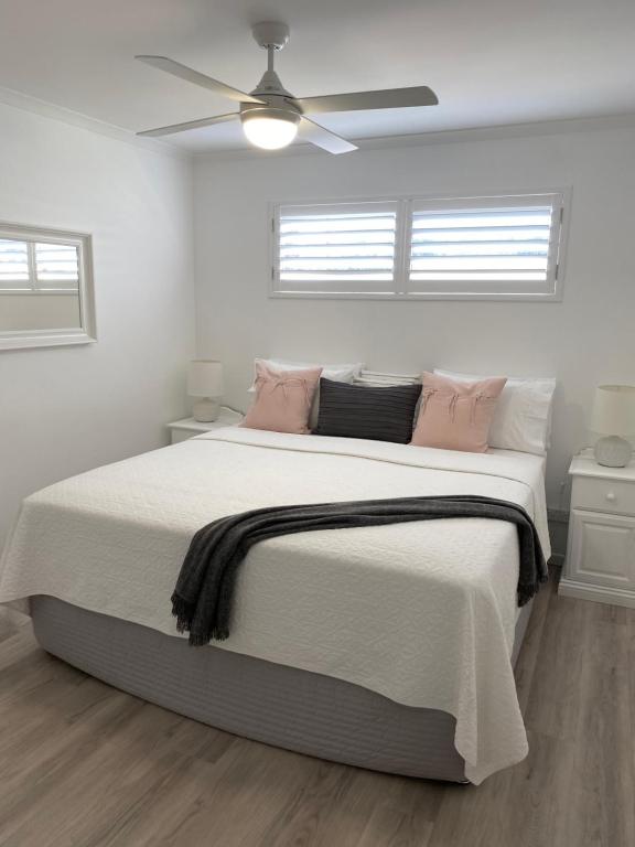 a white bedroom with a large bed with pink pillows at Rainbow Beach Dream Newly Renovated Stylish One Bedroom Apartment in Rainbow Beach