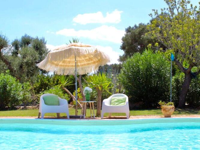 - deux chaises et un parasol à côté de la piscine dans l'établissement Holiday home, Carovigno, à Carovigno