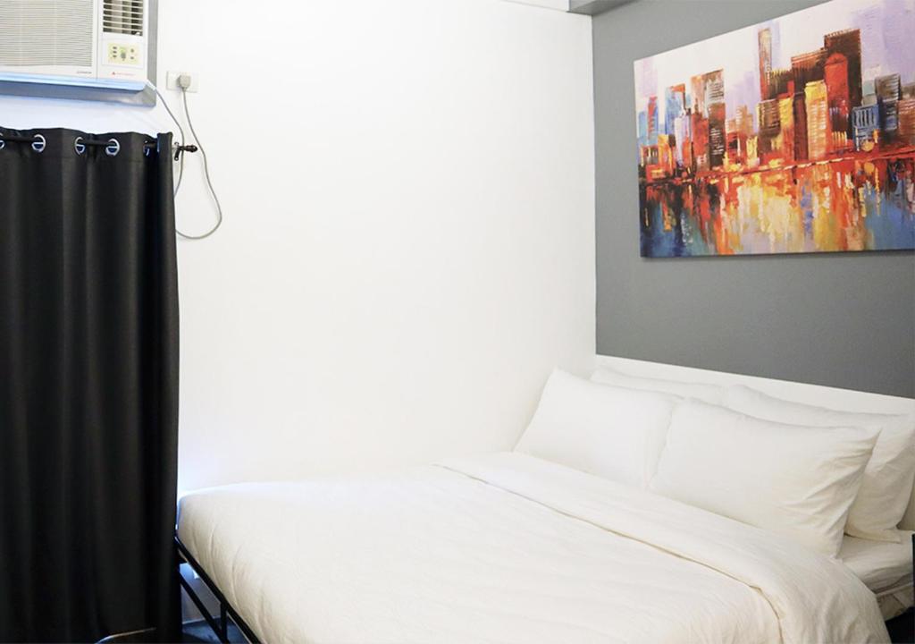 uma cama num quarto com uma pintura na parede em mySTAY Hotel BGC East em Manila