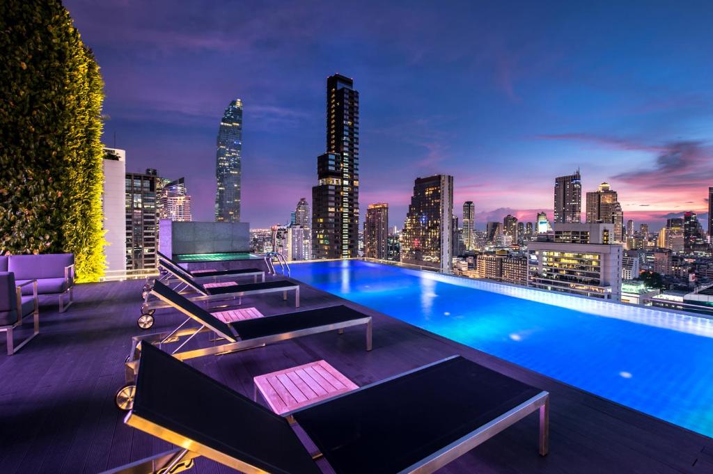 a rooftop pool with a city skyline at night at Amara Bangkok Hotel in Bangkok