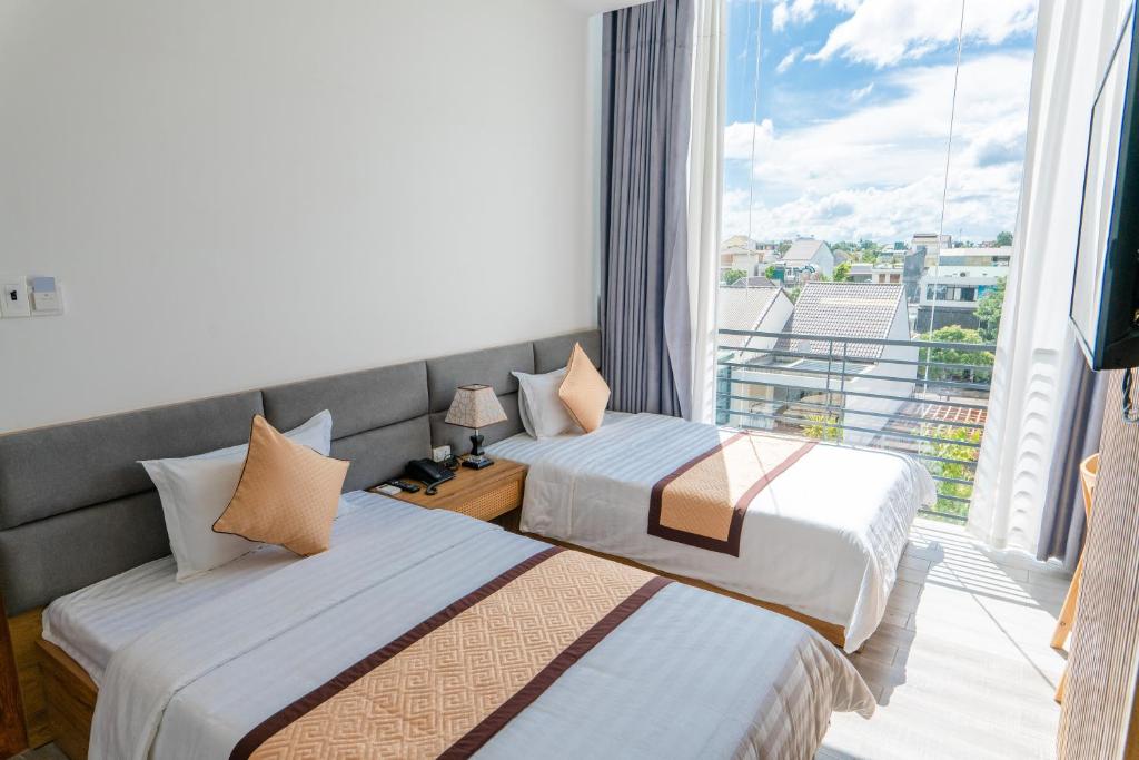 dwa łóżka w pokoju z dużym oknem w obiekcie Khang Hy Hotel w mieście Buôn Enao