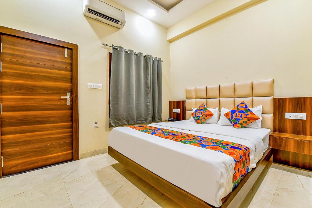 a bedroom with a large bed and a wooden door at FabExpress Dosa Plaza in Udaipur