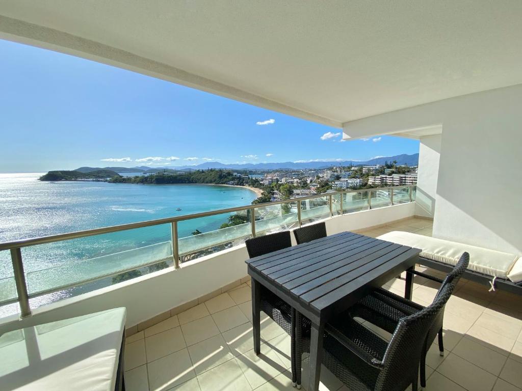 balcone con tavolo, sedie e vista sull'oceano di Casa Del Sole Apartments a Noumea