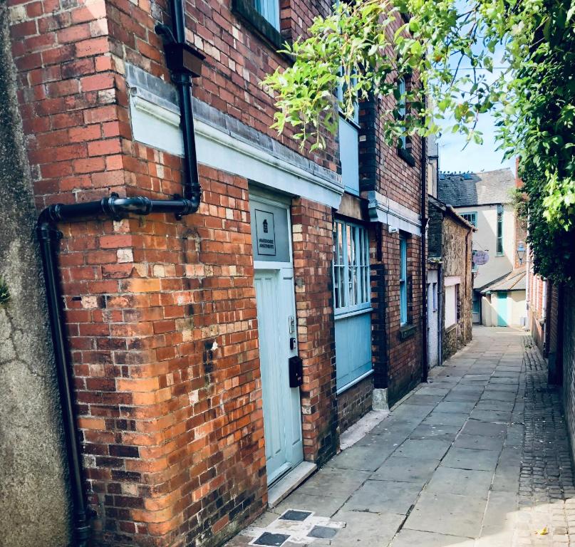 a brick alley with a white door on a brick building at Beautiful 1-Bed Apartment in central Ulverston in Ulverston