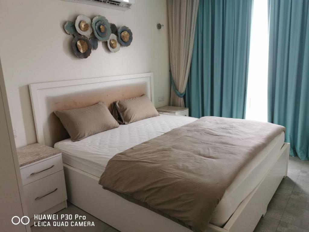 a bedroom with a large bed with blue curtains at Amazing 2BR pent house flat with mountain view in Muscat