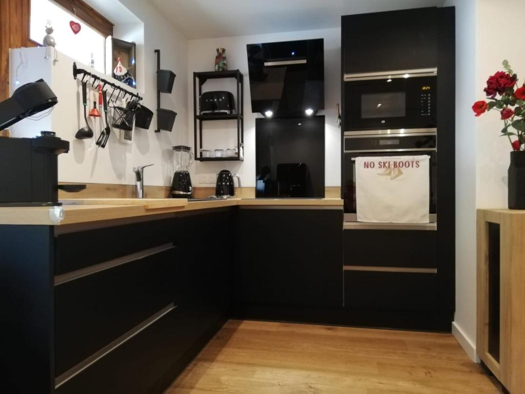 a kitchen with black cabinets and a microwave at Le Week-End 3 étoiles, plein centre ville in La Clusaz