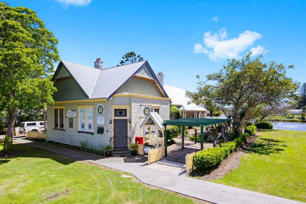 uma pequena casa branca com um telhado verde em The Old Bank Gladstone Licensed Restaurant & Boutique Accommodation em Hat Head