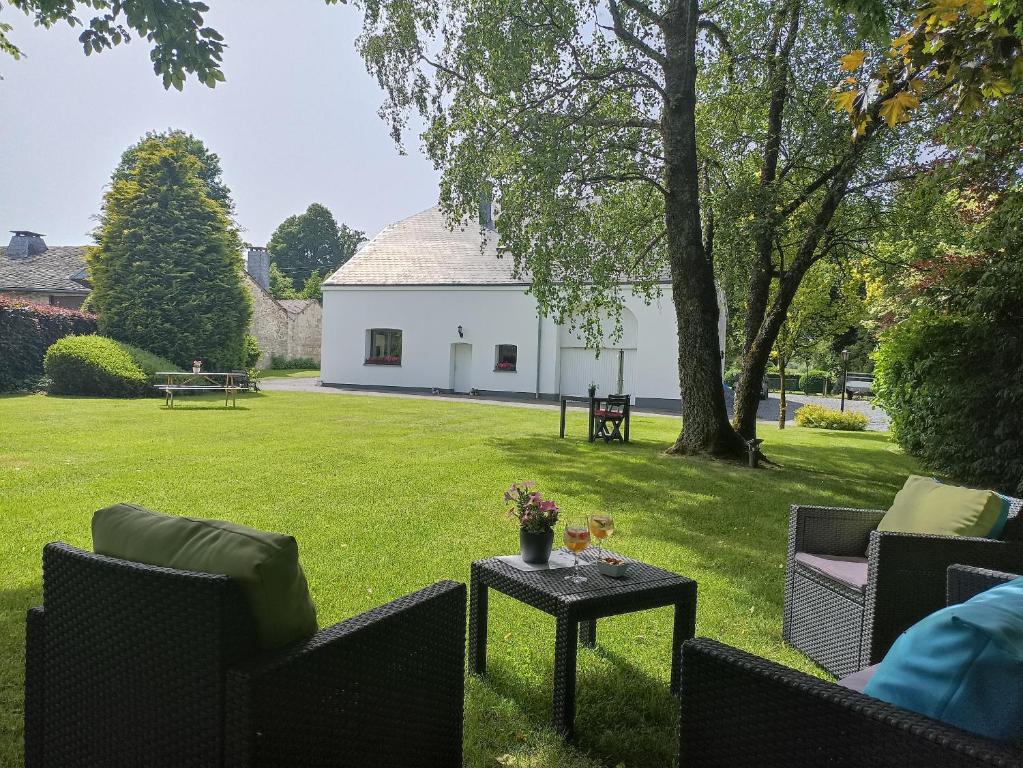 d'une terrasse avec des chaises et une table sur gazon. dans l'établissement Petites-Tailles - chambre d'hôtes, à Vielsalm