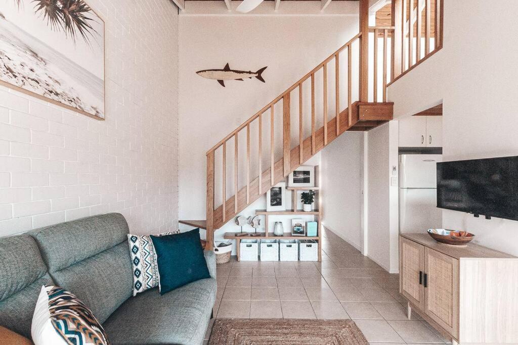 a living room with a couch and a staircase at Pippi Beach Apartment in Yamba