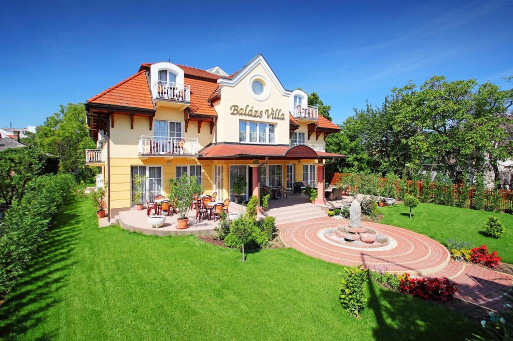 una gran casa amarilla con césped delante en Balazs Villa, en Balatonfüred