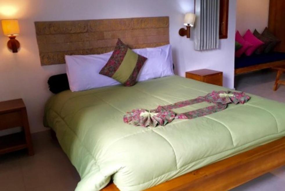 Un dormitorio con una gran cama verde con flores. en Terrasse du Lac Munduk en Munduk