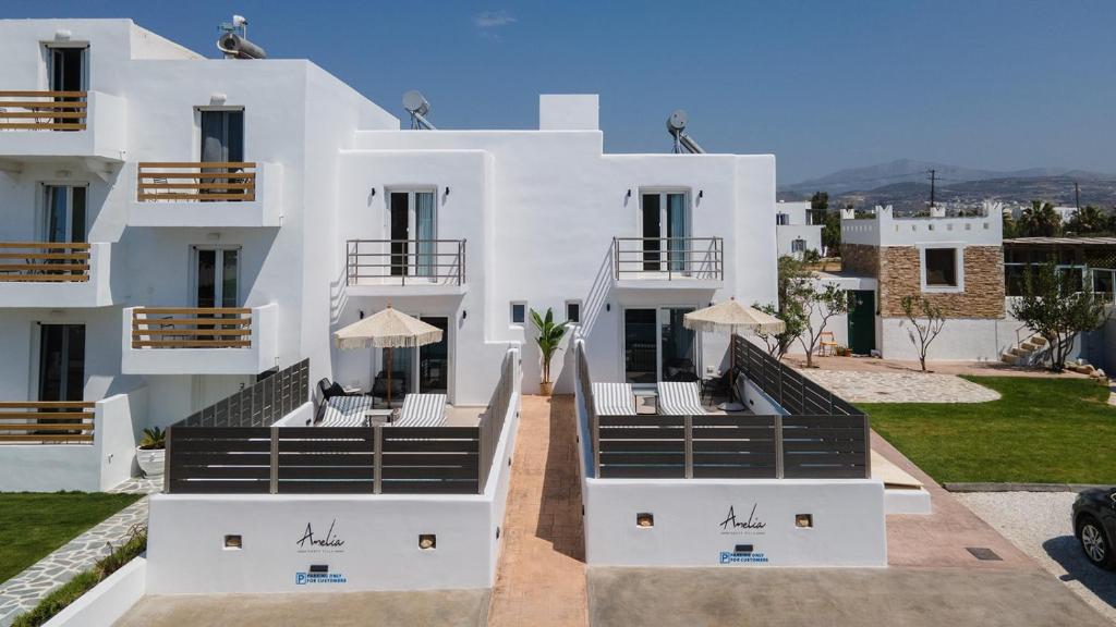 a white building with chairs and umbrellas in front of it at Amelia villas Naxos in Naxos Chora