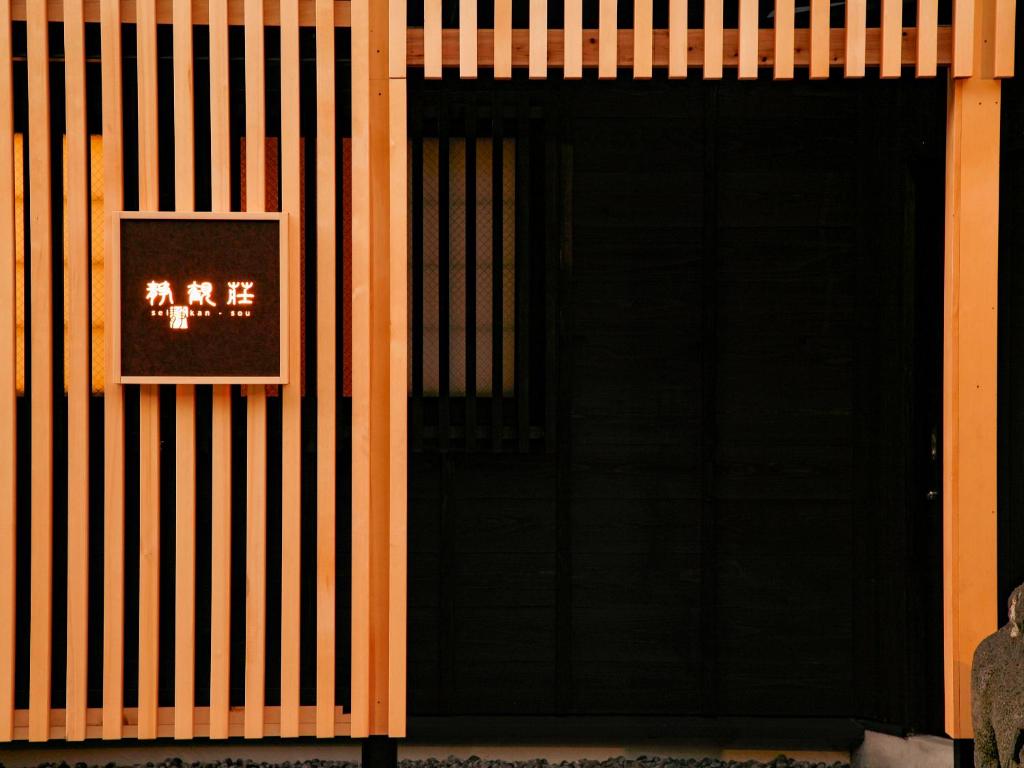 una puerta negra con una señal en el lateral de un edificio en Seikansou, en Hakone