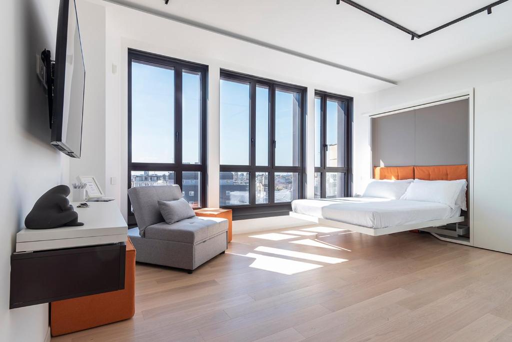 Schlafzimmer mit einem Bett, einem Stuhl und Fenstern in der Unterkunft easyhomes-Central Tower in Mailand