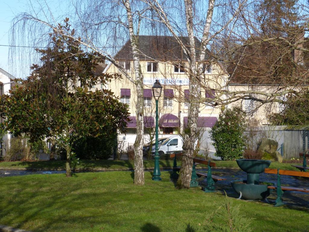 une cour avec des arbres et un bâtiment en arrière-plan dans l'établissement Hôtel Restaurant "Le Relais", à Courtenay