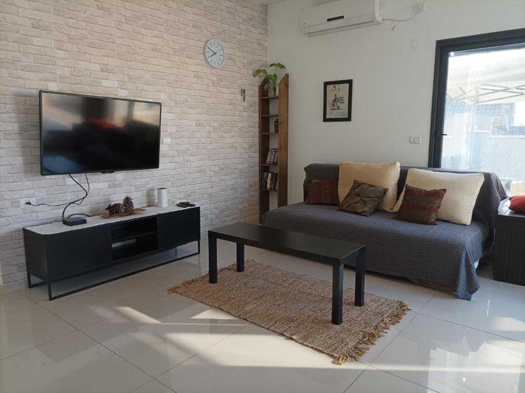 uma sala de estar com um sofá e uma televisão de ecrã plano em נוגה בגולן em Katzrin