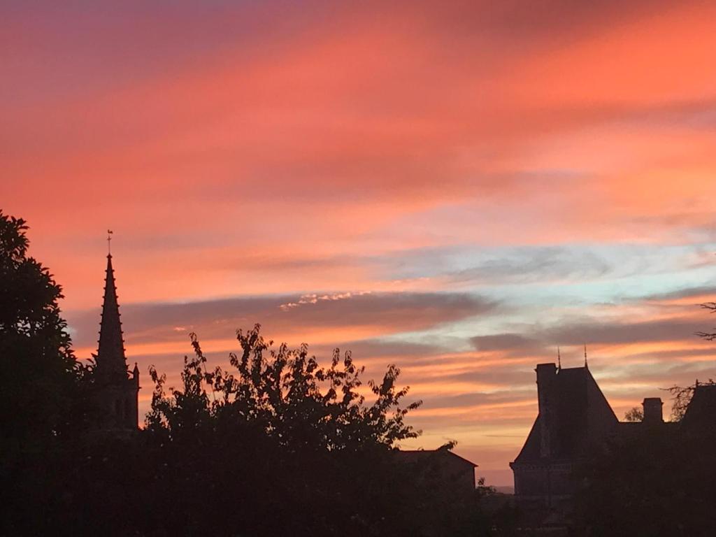 a sunset over a city with buildings and trees at Chambres d&#39;Hôtes Bienvenue in LʼAbsie