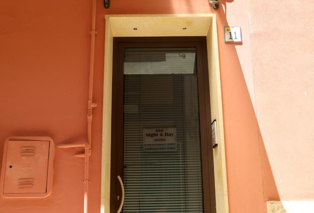 un cartel en la puerta de un edificio con un cartel en él en Night & Day, en Ragusa