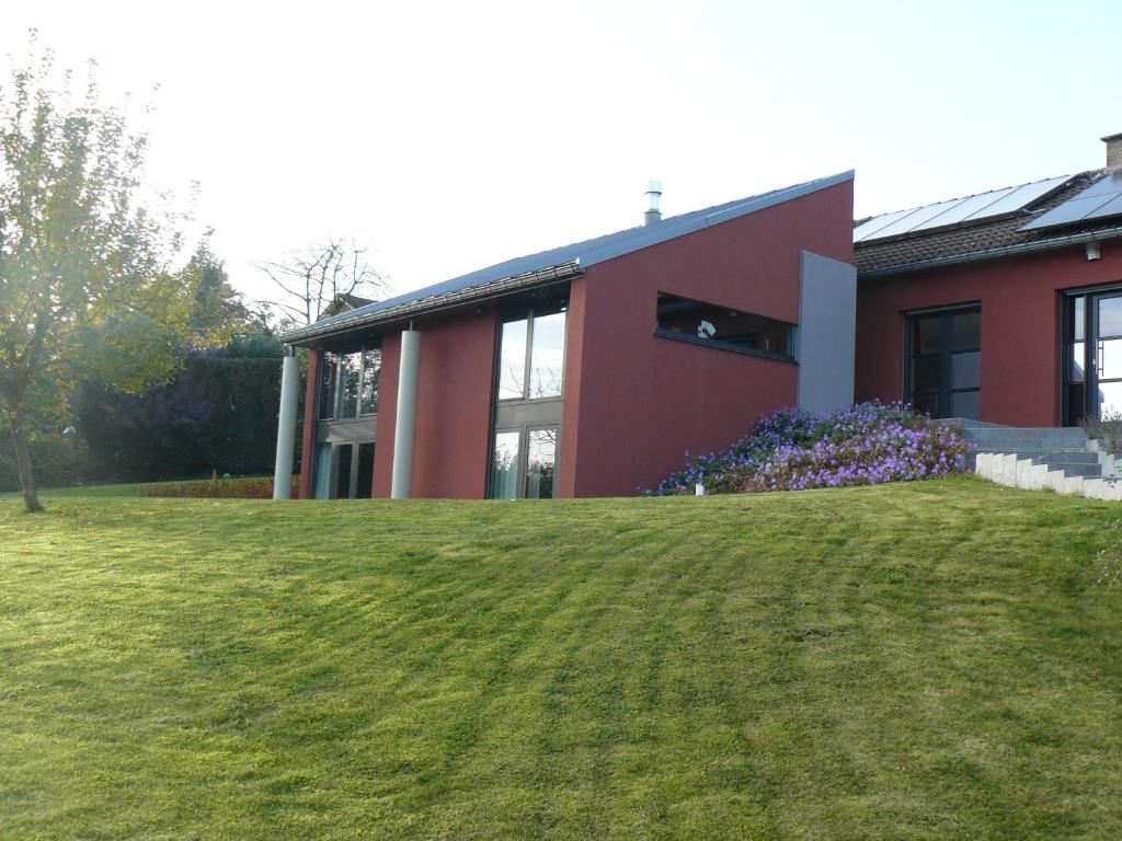 una casa roja con un césped verde delante de ella en Au Trouli, en Verviers