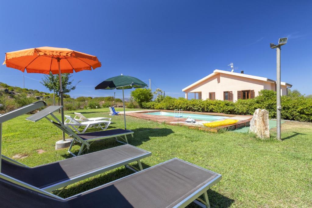un patio con sillas, una sombrilla y una piscina en Apartamento Vacanze Oleandro, en Olmedo