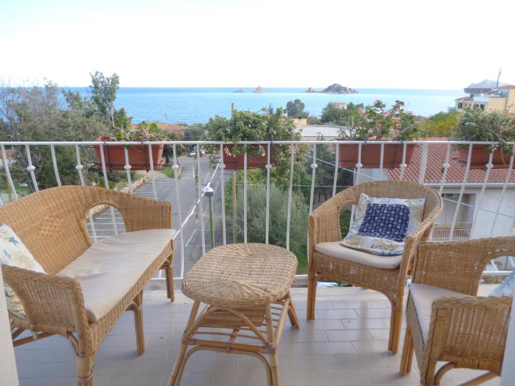 balcón con sillas de mimbre y mesa con vistas en Attico Bellavista, en Santa Maria Navarrese