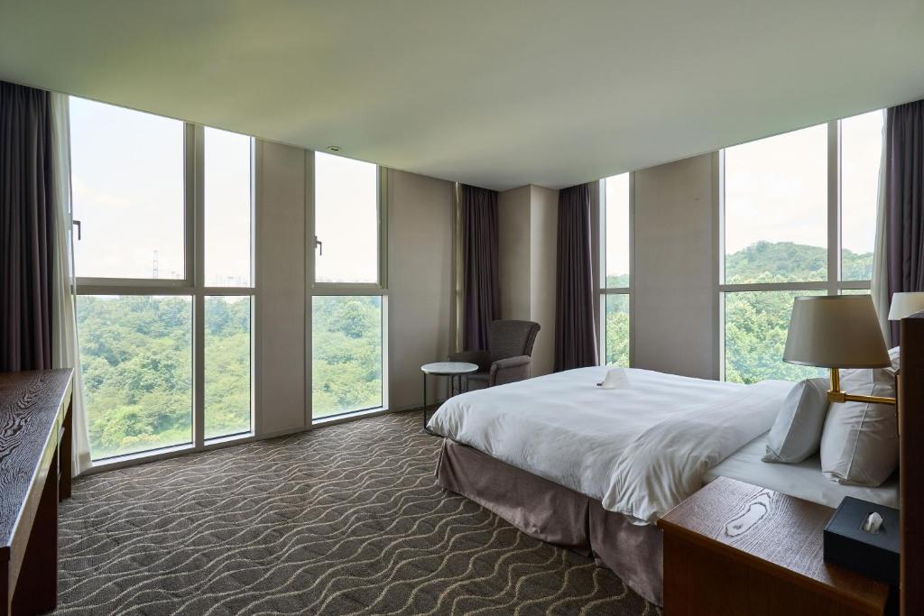 a hotel room with a bed and large windows at Hotel Square Ansan in Ansan