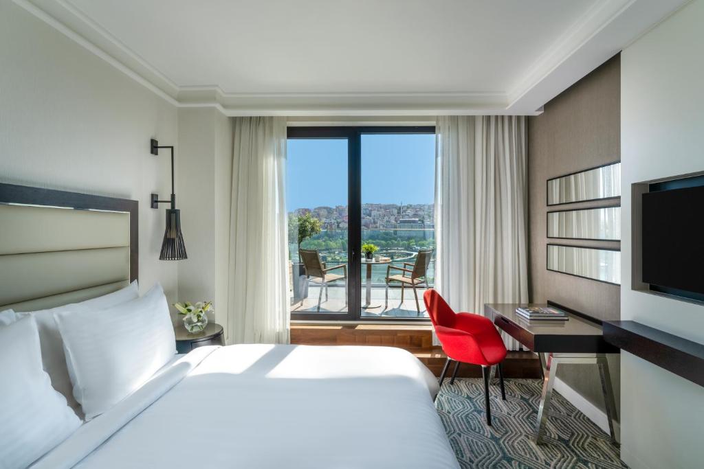 イスタンブールにあるモーベンピック イスタンブール ホテル ゴールデン ホーンのベッド、デスク、窓が備わるホテルルームです。