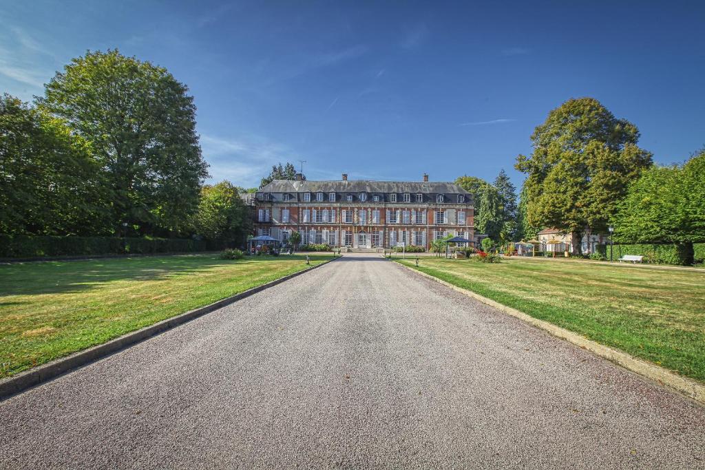 une route vide devant un grand bâtiment dans l'établissement B&B Château De La Houssoye, à La Houssoye