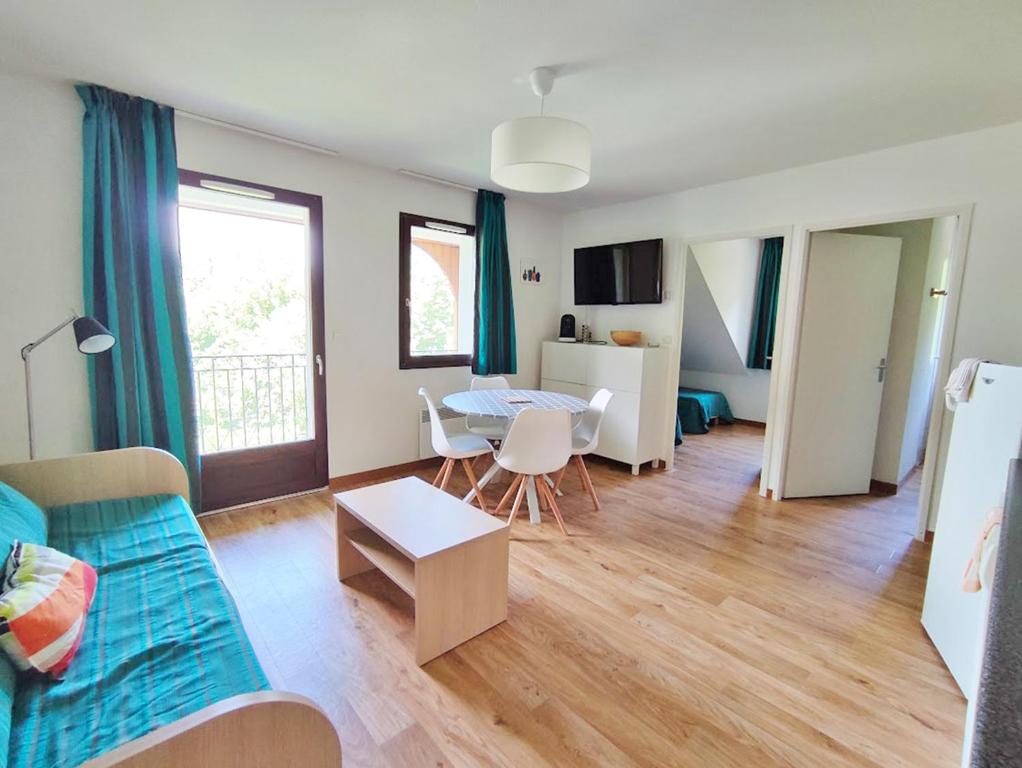 uma sala de estar com um sofá e uma mesa em Chez Marie-Laure, T3 résidence les Jardins de Ramel, parking, balcon, 4 personnes em Luchon