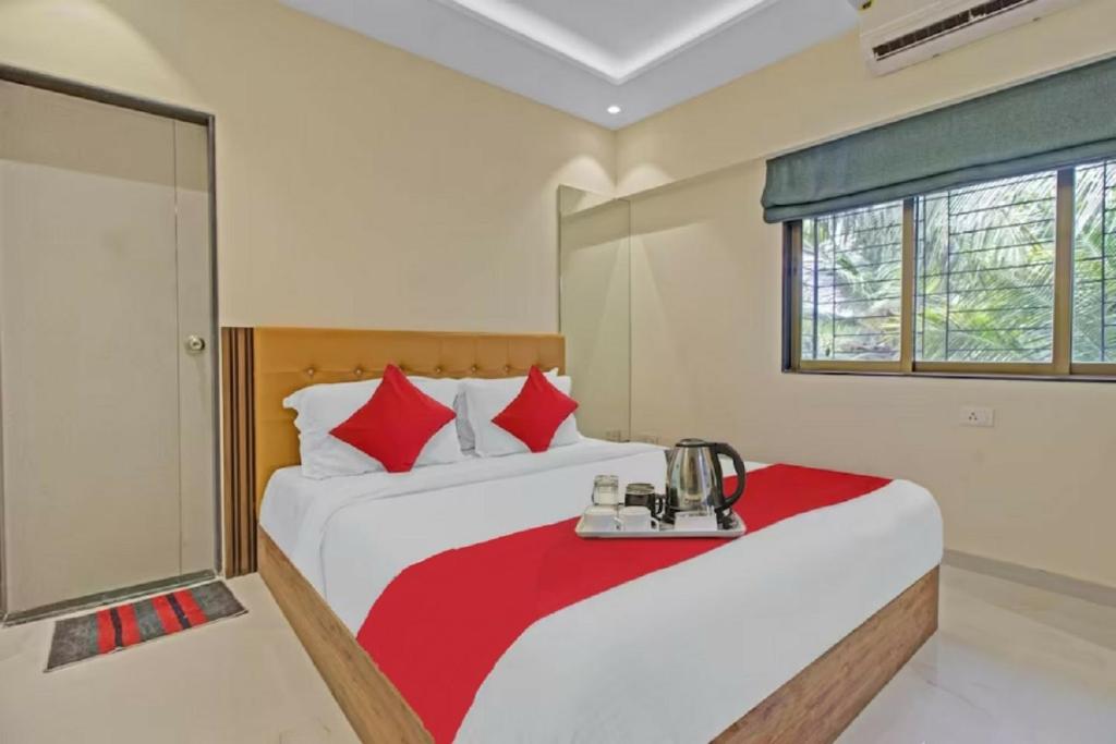 a bedroom with two beds with red pillows at Hotel Sunrise Juhu in Mumbai