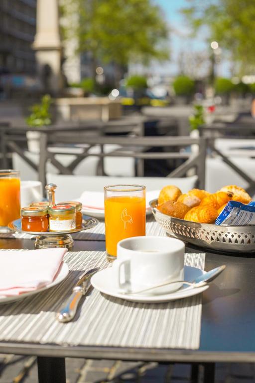 a table with a cup of coffee and a plate of food at Hôtel de la Cigogne in Geneva