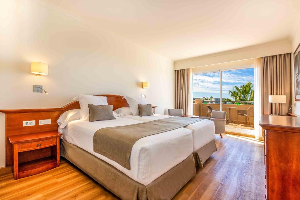 a hotel room with a large bed and a balcony at Valentin Sancti Petri in Chiclana de la Frontera