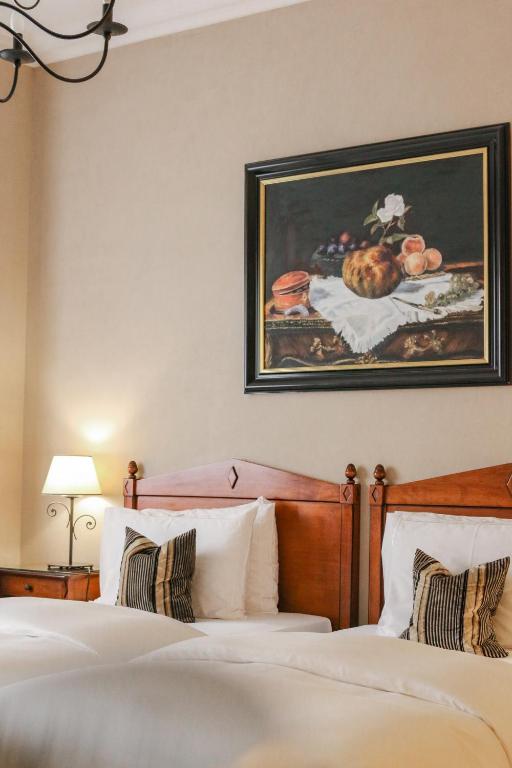 a bedroom with two beds and a painting on the wall at Hôtel de la Cigogne in Geneva