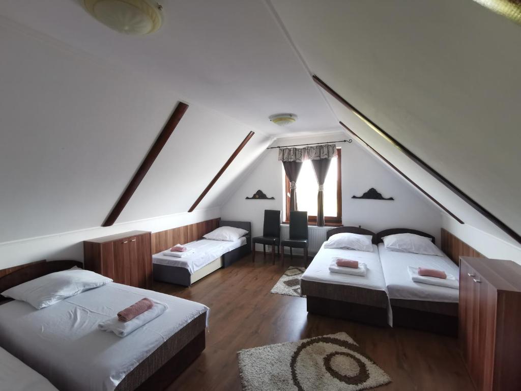 a attic room with two beds and a table at Merlot Borhotel és Látványpince in Edelény