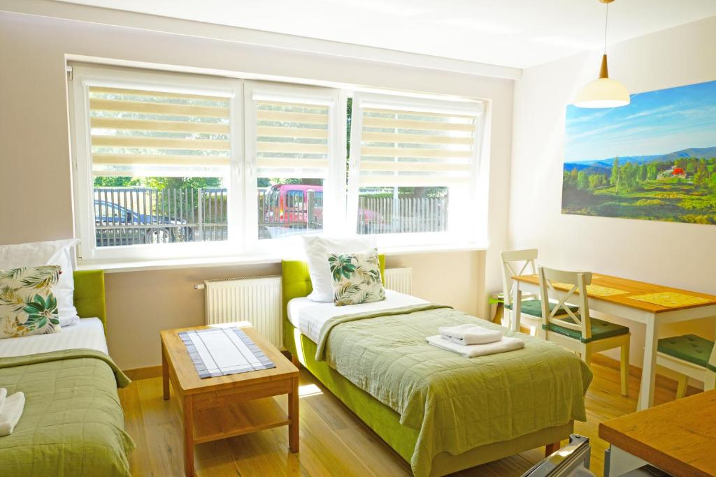 a bedroom with two beds and a table and a window at Nad Stawem in Ustroń
