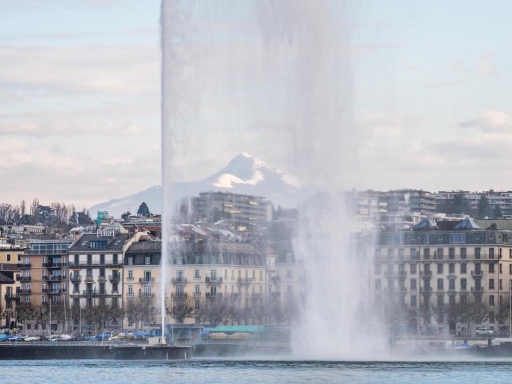 a fountain in the water in front of a city at Hôtel de la Cigogne in Geneva
