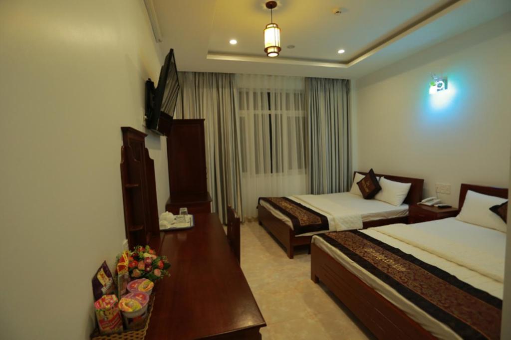 ein Hotelzimmer mit 2 Betten und einem Tisch in der Unterkunft Tan Truong Son Hotel in Dong Hoi