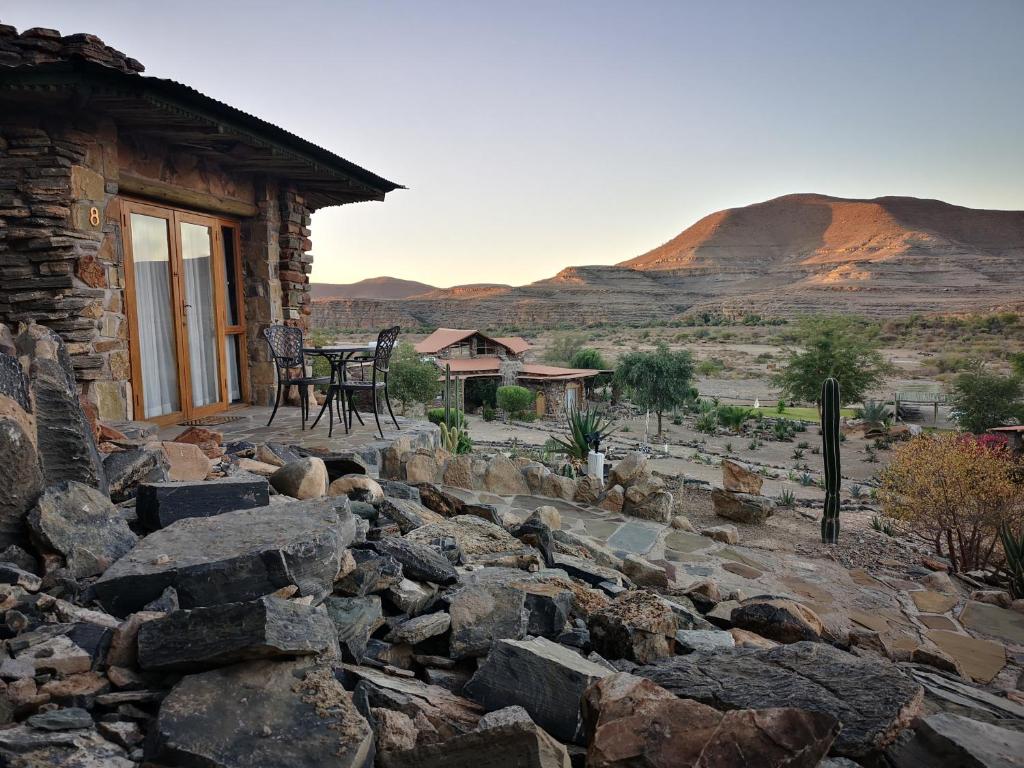 a stone house with a table and chairs in the desert at Zebra River Lodge in Maltahöhe