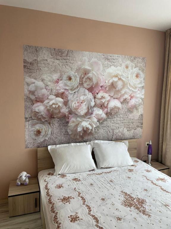 a bedroom with a painting of roses on the wall at Apartment Sanik in Varna City