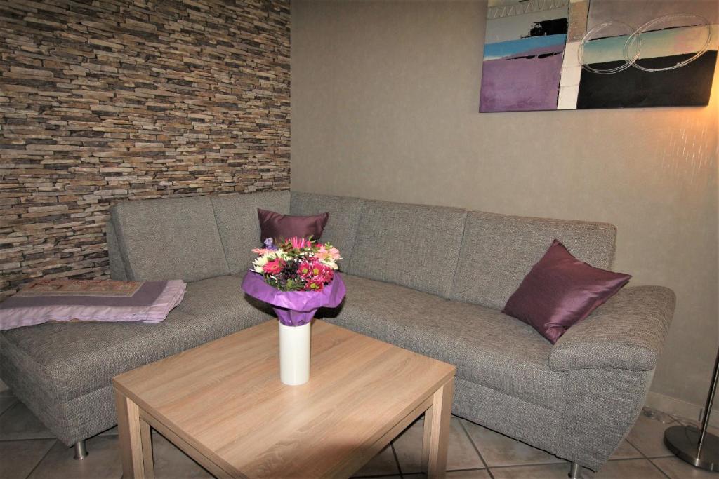 a living room with a couch and a table with flowers at Ferienwohnung Birkenhof in Volkesfeld
