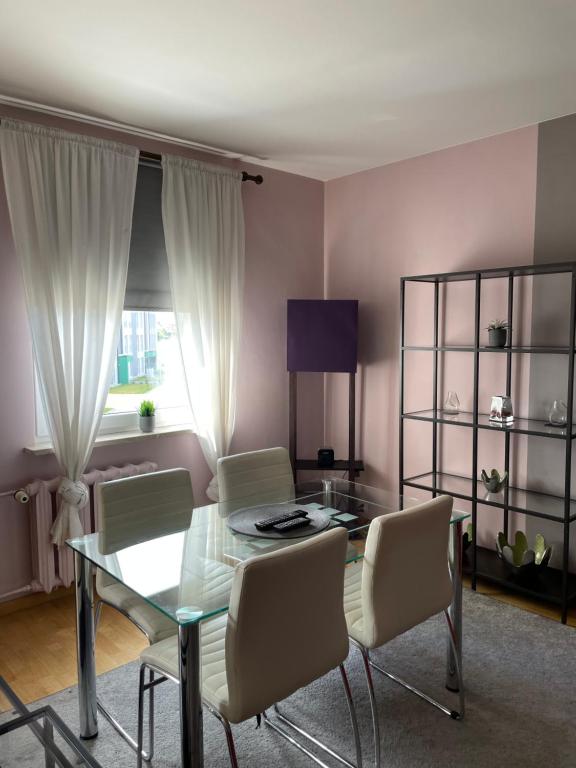- un salon avec une table et des chaises en verre dans l'établissement Apartament Kutrzeby, à Pobiedziska