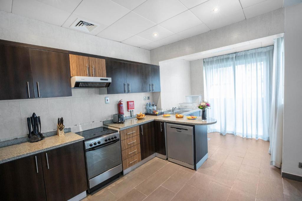 a kitchen with stainless steel appliances and brown cabinets at City Premiere Hotel Apartments - Dubai in Dubai