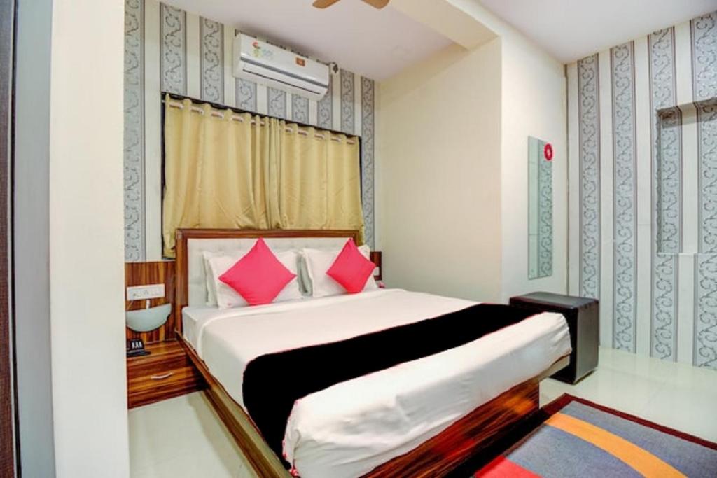 a bedroom with a large bed with pink pillows at Hotel De Classico Juhu in Mumbai