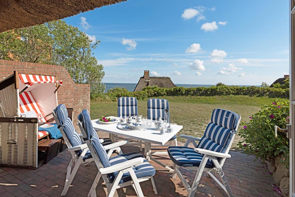 una mesa y sillas en un patio con vistas al océano en Urlaubsglück, en List