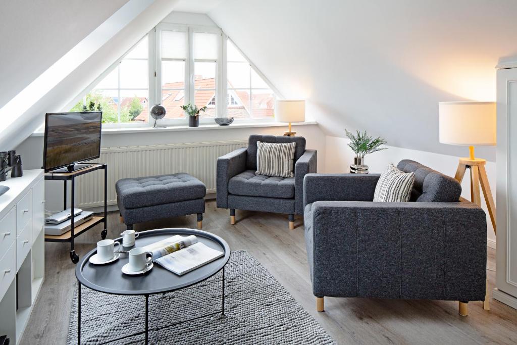 een woonkamer met 2 stoelen en een televisie bij Hafenblick Haus Senhuk in List