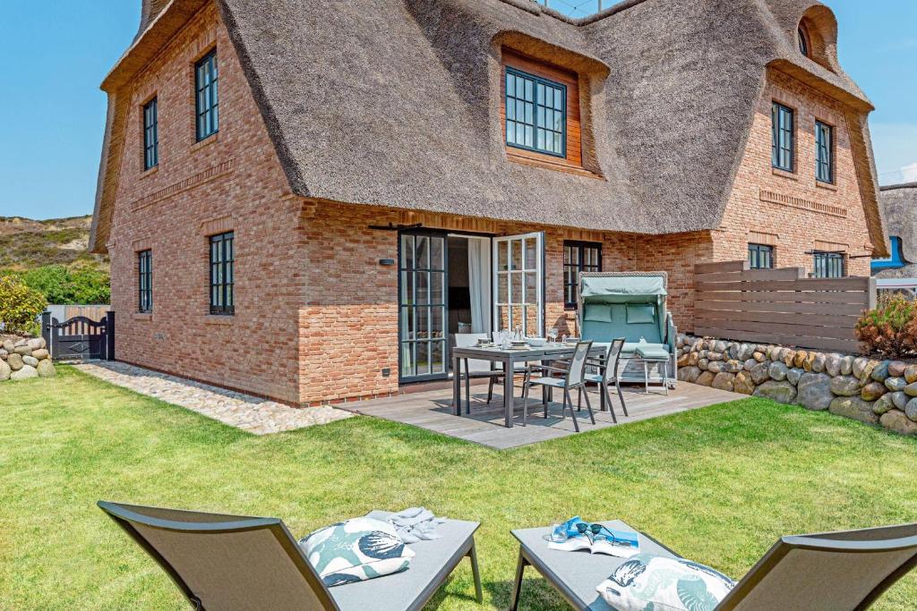 a house with a thatched roof with a table and chairs at Sunset in List