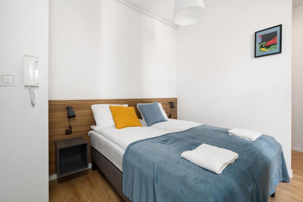 sypialnia z dużym łóżkiem z żółtymi i niebieskimi poduszkami w obiekcie Kwiatowa Apartments Poznań City Center by Noclegi Renters w Poznaniu